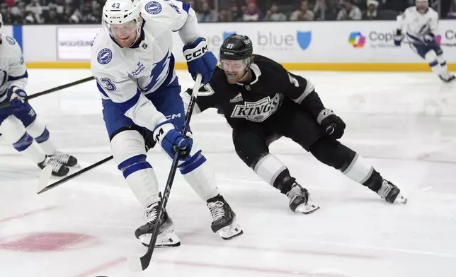 Tampa Bay Lightning defenseman Darren Raddysh, left, moves the puck while Los Angeles Kings left wing Warren Foegele puts pressure on him during the second period of an NHL hockey game, Saturday, Jan. 4, 2025, in Los Angeles. (AP Photo/Mark J. Terrill)