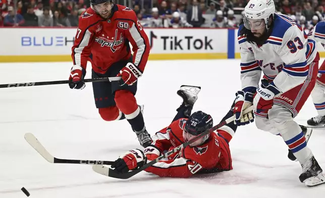 Washington Capitals center Lars Eller (20) bats the puck away from New York Rangers center Mika Zibanejad (93) during the second period of an NHL hockey game Saturday, Jan. 4, 2025, in Washington. (AP Photo/John McDonnell)
