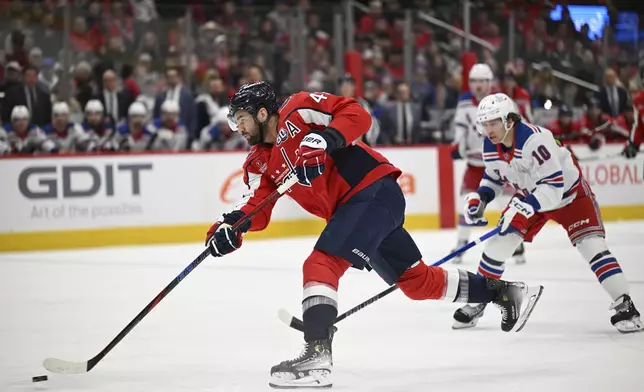 Washington Capitals right wing Tom Wilson, left, takes a shot as New York Rangers left wing Artemi Panarin (10) looks on during the first period of an NHL hockey game Saturday, Jan. 4, 2025, in Washington. (AP Photo/John McDonnell)