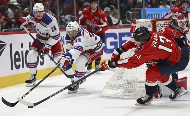 Washington Capitals left wing Jakub Vrana, right, reaches to control the puck against New York Rangers center Sam Carrick (39) during the second period of an NHL hockey game Saturday, Jan. 4, 2025, in Washington. (AP Photo/John McDonnell)