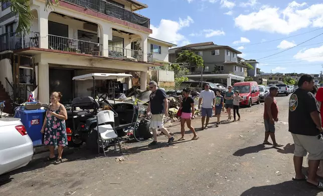 People walk past the home where a New Year's Eve fireworks explosion killed and injured people, Wednesday, Jan. 1, 2025, in Honolulu. (AP Photo/Marco Garcia)