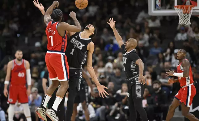 San Antonio Spurs' Victor Wembanyama, center, collides with Los Angeles Clippers' James Harden during the first half of an NBA basketball game, Tuesday, Dec. 31, 2024, in San Antonio. (AP Photo/Darren Abate)