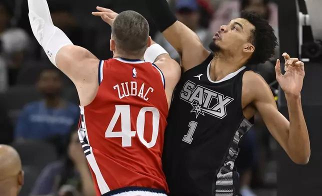 San Antonio Spurs' Victor Wembanyama (1) moves to block a shot-attempt by Los Angeles Clippers' Ivica Zubac (40) during the first half of an NBA basketball game, Tuesday, Dec. 31, 2024, in San Antonio. (AP Photo/Darren Abate)