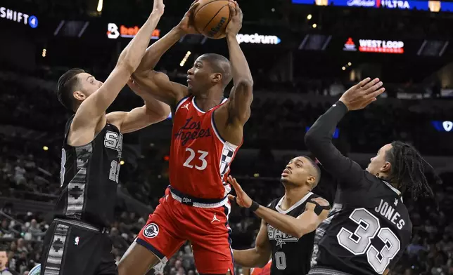 Los Angeles Clippers' Kai Jones (23) tangles with San Antonio Spurs' Zach Collins, left, Keldon Johnson (0) and Tre Jones (33) during the second half of an NBA basketball game, Tuesday, Dec. 31, 2024, in San Antonio. (AP Photo/Darren Abate)