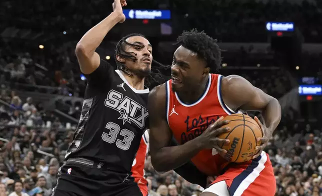 Los Angeles Clippers' Kobe Brown, right, drives against San Antonio Spurs' Tre Jones (33) during the second half of an NBA basketball game, Tuesday, Dec. 31, 2024, in San Antonio. (AP Photo/Darren Abate)