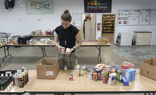 Nick Koenig, a University of Idaho doctoral student who teaches in climate change and sociology, sorts canned goods as he volunteers on Thursday, Dec. 12, 2024 for the West Side Food Pantry near the University of Idaho campus in Moscow, Idaho. (AP Photo/Ted S. Warren)