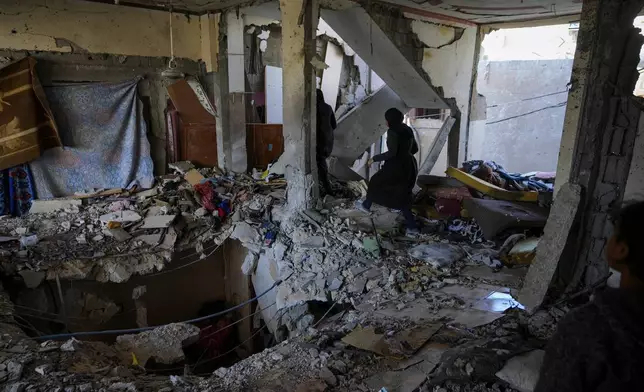 Palestinian women look at a damaged residential building following an overnight Israeli strike in Deir al-Balah, Gaza Strip, Thursday, Jan. 9, 2025. (AP Photo/Abdel Kareem Hana)