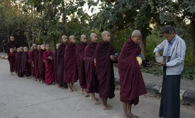 A Buddhist monk receives alms from a devotee Saturday, Feb. 1, 2025, in Naypyitaw, Myanmar. (AP Photo/Aung Shine Oo)