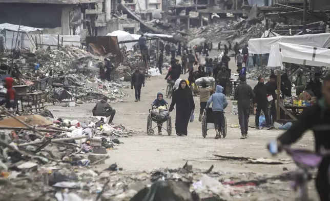 Pedestrians walk along a road lined with few stands selling goods, amid widespread destruction caused by the Israeli military's ground and air offensive in Gaza City's Jabaliya refugee camp, Friday, Feb. 7, 2025. (AP Photo/Jehad Alshrafi)