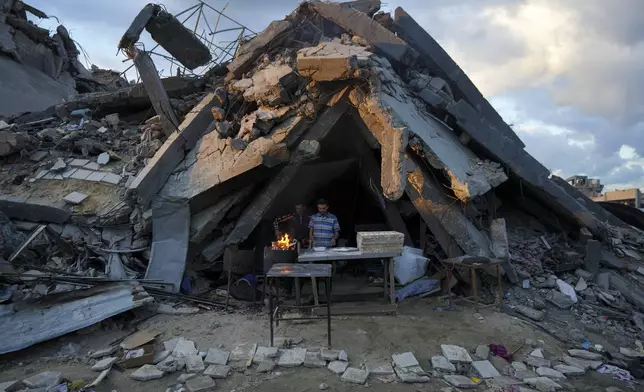 A man sells bread under the destruction of his bakery destroyed by the Israeli air and ground offensive in Jabaliya, Gaza Strip, Wednesday, Feb. 5, 2025. (AP Photo/Abdel Kareem Hana)