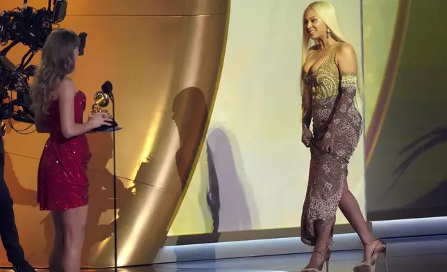 Taylor Swift, left, presents the award for best country album to Beyonce for "COWBOY CARTER" during the 67th annual Grammy Awards on Sunday, Feb. 2, 2025, in Los Angeles. (AP Photo/Chris Pizzello)