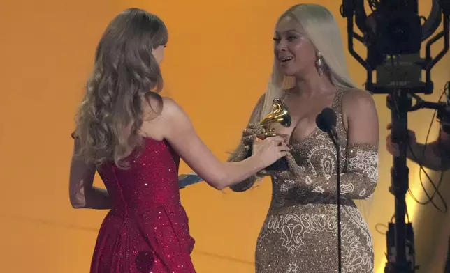 Taylor Swift, left, presents the award for best country album to Beyonce for "COWBOY CARTER" during the 67th annual Grammy Awards on Sunday, Feb. 2, 2025, in Los Angeles. (AP Photo/Chris Pizzello)