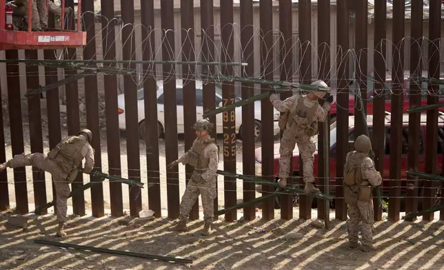 U.S. Marines install barbed wire along the border fence Friday, Jan. 31, 2025, in San Diego. (AP Photo/Jae C. Hong)