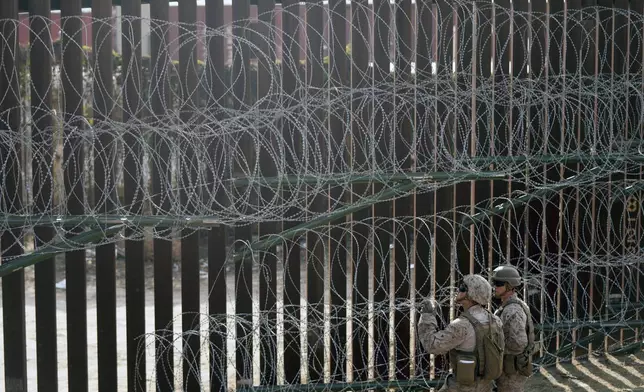 U.S. Marines install barbed wire along the border fence Friday, Jan. 31, 2025, in San Diego. (AP Photo/Jae C. Hong)