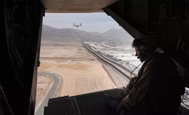 Gunnery Sgt. Derek Levi, right, looks down at the U.S. Mexico border aboard a Marines helicopter Friday, Jan. 31, 2025, near San Diego. (AP Photo/Jae C. Hong)