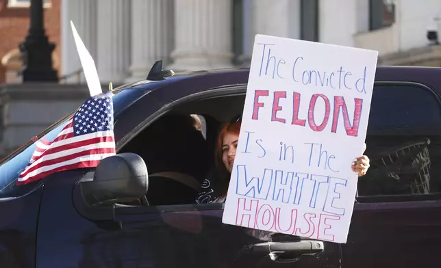 A motorist waves a placard in support of participants in a political protest outside the State Capitol Wednesday, Feb. 5, 2025, in Denver. (AP Photo/David Zalubowski)