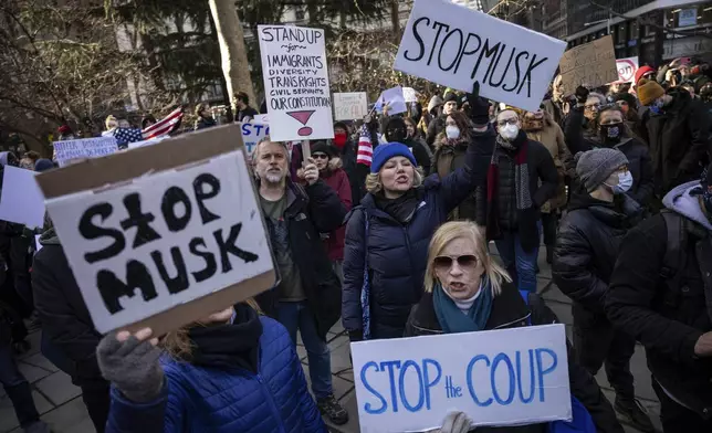 Demonstrators raise signs during a protest outside City Hall, Wednesday, Feb. 5, 2025, in New York. (AP Photo/Yuki Iwamura)