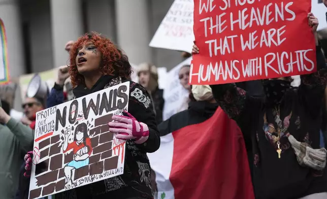 People wave signs as they gather to protest against the Trump administration on the steps of the Washington State Capitol building Wednesday, Feb. 5, 2025, in Olympia, Wash. (AP Photo/Lindsey Wasson)