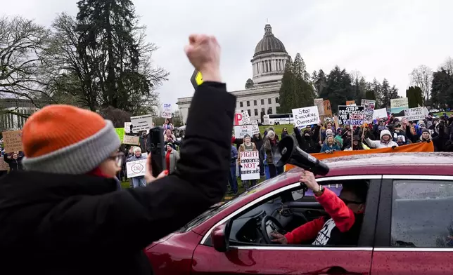 A driver sticks a bullhorn out their window and honks in support as people gather to protest against the Trump administration and Project 2025 near the Washington State Capitol building Wednesday, Feb. 5, 2025, in Olympia, Wash. (AP Photo/Lindsey Wasson)