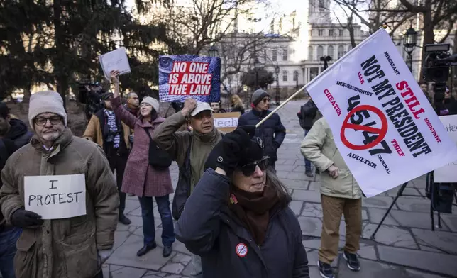 Demonstrators raise signs during a protest outside City Hall, Wednesday, Feb. 5, 2025, in New York. (AP Photo/Yuki Iwamura)