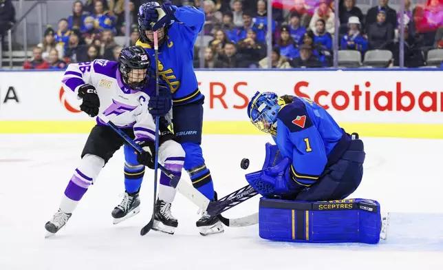 Minnesota Frost's Kendall Coyne-Schofield, left, tries to get a puck past Toronto Sceptres goaltender Raygan Kirk as Sceptres' Blayre Turnbull defends during the first period of a PWHL hockey game in Toronto, Tuesday, Feb. 11, 2025. (Cole Burston/The Canadian Press via AP)