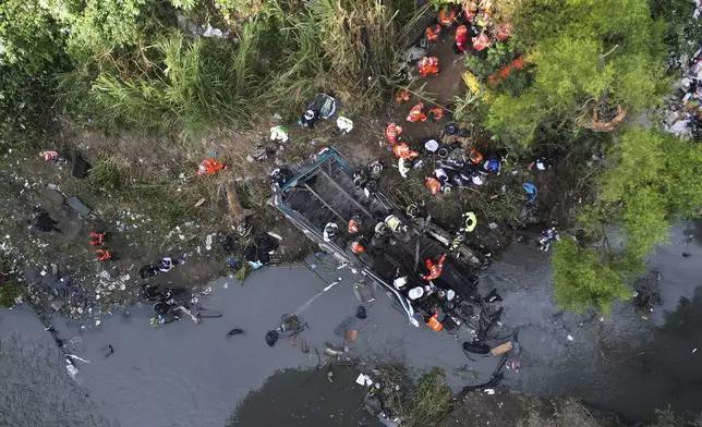 Firefighters work the scene of a fatal bus crash after it fell from a bridge on the outskirts of Guatemala City, Monday, Feb. 10, 2025. (AP Photo/Moises Castillo)