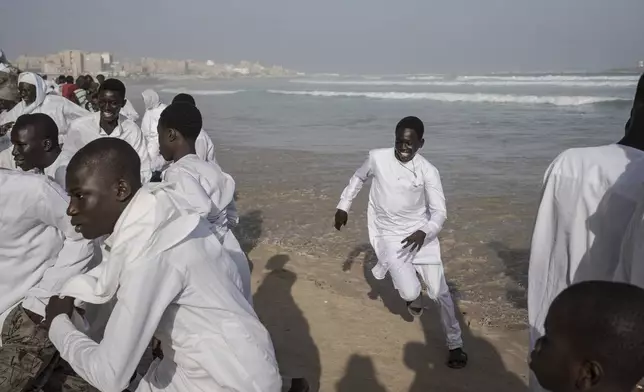 Dressed in white robes to symbolize purity and equality before God, followers from the Layene brotherhood commemorate the first public appearance of their founder Seydina Limamou Laye in 1884 at Yoff's beachside mosque in Dakar, Senegal, Friday, Jan. 31, 2025. (AP Photo/Annika Hammerschlag)