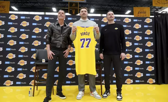 From left to right, Los Angeles Lakers general manager Rob Pelinka, Luka Doncic, and head coach JJ Redick pose for photos during an introductory NBA basketball press conference Tuesday, Feb. 4, 2025, in El Segundo, Calif. (AP Photo/Jae C. Hong)
