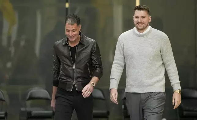 Los Angeles Lakers' Luka Doncic, right, walks to the podium with general manger Rob Pelinka during an introductory NBA basketball press conference Tuesday, Feb. 4, 2025, in El Segundo, Calif. (AP Photo/Jae C. Hong)