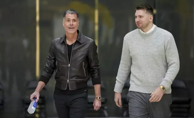 Los Angeles Lakers' Luka Doncic, left, walks to the podium with general manger Rob Pelinka during an introductory NBA basketball press conference Tuesday, Feb. 4, 2025, in El Segundo, Calif. (AP Photo/Jae C. Hong)