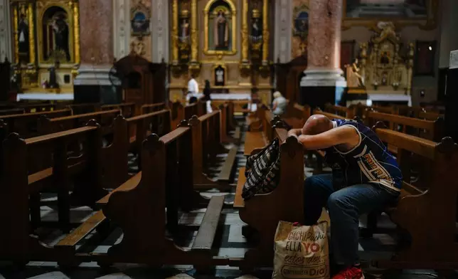 A man bows his head on a pew at San José de Flores basilica, Buenos Aires, Argentina, where Pope Francis worshipped as a youth, Sunday, Feb. 23, 2025. (AP Photo/Natacha Pisarenko)