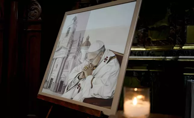 A candle sits alongside a painting of Pope Francis at San José de Flores basilica, Buenos Aires, Argentina, where he worshipped as a youth, Sunday, Feb. 23, 2025. (AP Photo/Natacha Pisarenko)