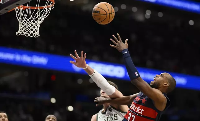 Washington Wizards forward Khris Middleton (32) is fouled by Milwaukee Bucks center Brook Lopez, second from right, as he goes to the basket during the first half of an NBA basketball game, Friday, Feb. 21, 2025, in Washington. (AP Photo/Nick Wass)