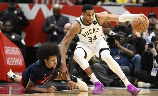 Milwaukee Bucks forward Giannis Antetokounmpo (34) and Washington Wizards forward Kyshawn George, left, fall during the first half of an NBA basketball game, Friday, Feb. 21, 2025, in Washington. (AP Photo/Nick Wass)