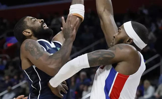 Dallas Mavericks guard Kyrie Irving, left, shoots against Detroit Pistons forward Paul Reed, right, during the first half of an NBA basketball game Friday, Jan. 31, 2025, in Detroit. (AP Photo/Duane Burleson)
