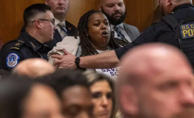 A protester is removed while calling out for rights for transgender and other students, during a Health, Education, and Labor Committee hearing on the nomination of Linda McMahon to be Secretary of Education, Thursday, Feb. 13, 2025, in Washington. (AP Photo/Jacquelyn Martin)