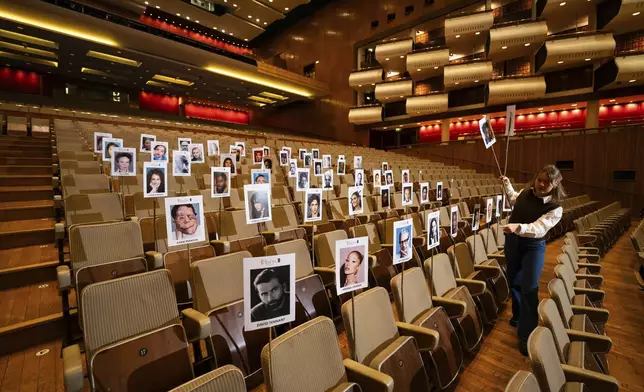 Publicist Abbie Gainher places placards with the images of actors on seats ahead of the BAFTA film awards in London, Wednesday, Feb. 12, 2024. (Photo by Scott A Garfitt/Invision/AP)