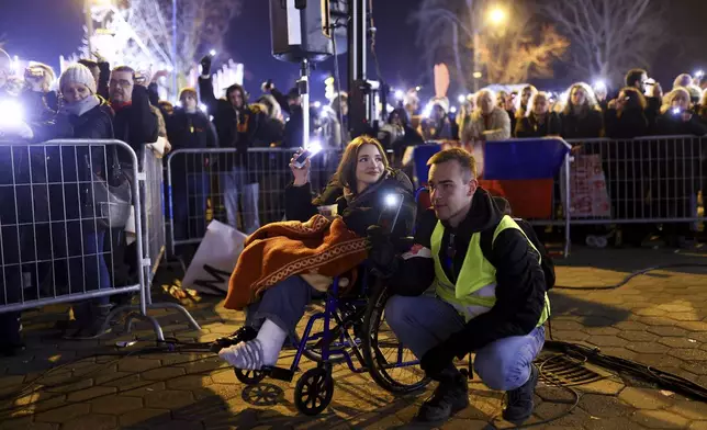 People hold up their mobile phone lights during a minute of silence ceremony as they block the bridge during a protest over the collapse of a concrete canopy that killed multiple people more than two months ago, in Novi Sad, Serbia, Sunday, Feb. 2, 2025. (AP Photo/Armin Durgut)