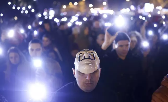 People hold up their mobile phone lights during a minute of silence ceremony as they block the bridge and protest over the collapse of a concrete canopy that killed 15 people more than two months ago, in Novi Sad, Serbia, Sunday, Feb. 2, 2025. (AP Photo/Armin Durgut)