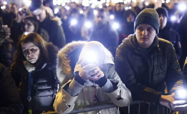 People hold up their mobile phone lights during a minute of silence ceremony as they block the bridge and protest over the collapse of a concrete canopy that killed 15 people more than two months ago, in Novi Sad, Serbia, Sunday, Feb. 2, 2025. (AP Photo/Armin Durgut)
