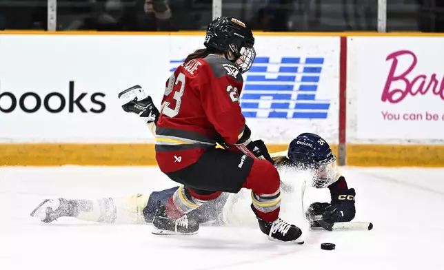 Montreal Victoire's Abigail Boreen (24) falls as Ottawa's Jocelyne Larocque (23) defends during second period PWHL hockey action in Ottawa, on Saturday, Feb. 22, 2025. (Justin Tang/The Canadian Press via AP)