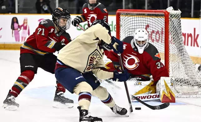 Ottawa Charge goaltender Gwyneth Philips (33) makes a save on Montreal Victoire's Kristin O'Neill (43) as Charge's Jincy Roese (71) defends, during second period PWHL hockey action in Ottawa, on Saturday, Feb. 22, 2025. (Justin Tang/The Canadian Press via AP)