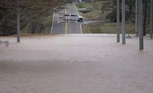 A vehicle turns around at a road closure for flooding along Dunbar Cave Rd., Sunday, Feb. 16, 2025, in Clarksville, Tenn. (AP Photo/George Walker IV)