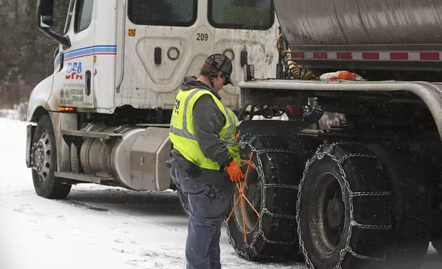 A truck driver checks her rig after chaining up along the clogged westbound lanes of Interstate 70 as skiers head to the mountains for the Presidents' Day weekend Friday, Feb. 14, 2025, near Georgetown, Colo. (AP Photo/David Zalubowski)