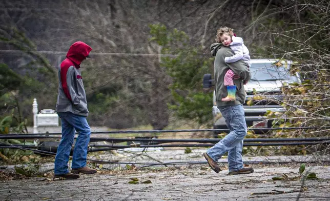 A man carries a little girl to a truck from a house amidst debris from a storm in east Tuscumbia, Ala., Sunday, Feb. 16, 2025. (Dan Busey/The TimesDaily via AP)