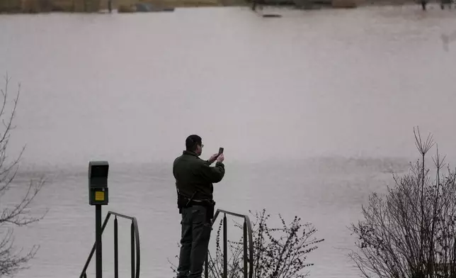 A park ranger takes picture of flood water at Dunbar Cave State Park, Sunday, Feb. 16, 2025, in Clarksville, Tenn. (AP Photo/George Walker IV)