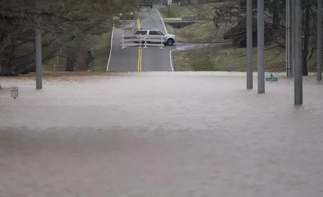 A vehicle turns around at a road closure for flooding along Dunbar Cave Rd., Sunday, Feb. 16, 2025, in Clarksville, Tenn. (AP Photo/George Walker IV)