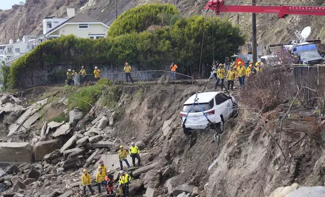An emergency vehicle is pulled out of the water a day after it was pushed into the surf by a debris flow caused by heavy rainfall, Friday, Feb. 14, 2025, in Malibu, Calif. (AP Photo/Damian Dovarganes)