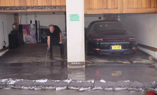Scott Von hoses mud off his garage in his property after a storm Friday, Feb. 14, 2025, in Malibu, Calif. (AP Photo/Damian Dovarganes)