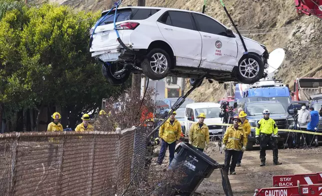 An emergency vehicle is pulled out of the water a day after it was pushed into the surf by debris flow caused by heavy rain, Friday, Feb. 14, 2025, in Malibu, Calif. (AP Photo/Damian Dovarganes)